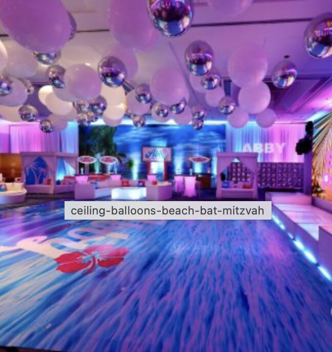 Beach-themed dance floor under a balloon ceiling